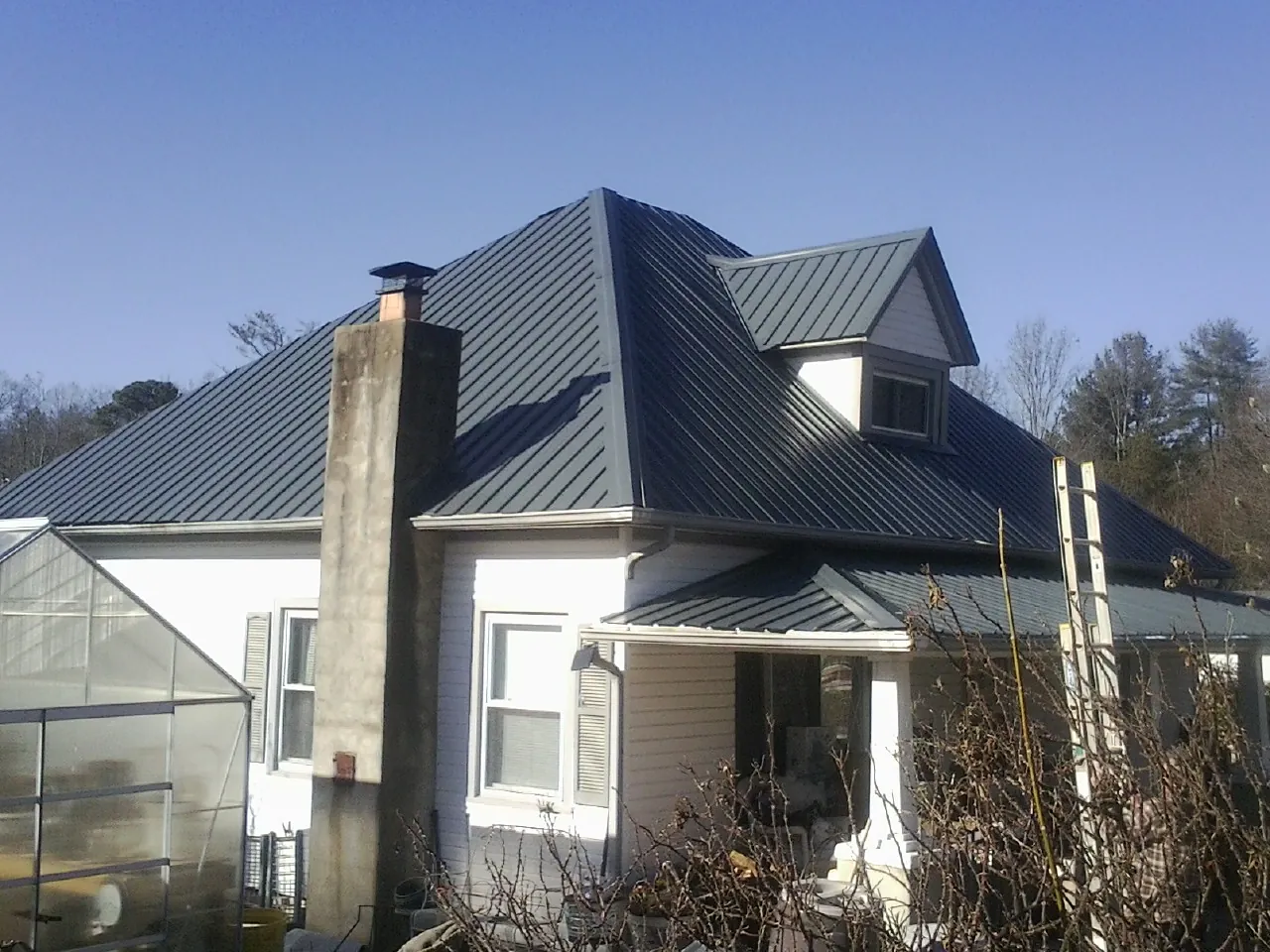 Dark blue standing seam metal roof on a white farmhouse with dormer — Slate & Tile Roof Repair by Roofing Brothers in Old Saybrook