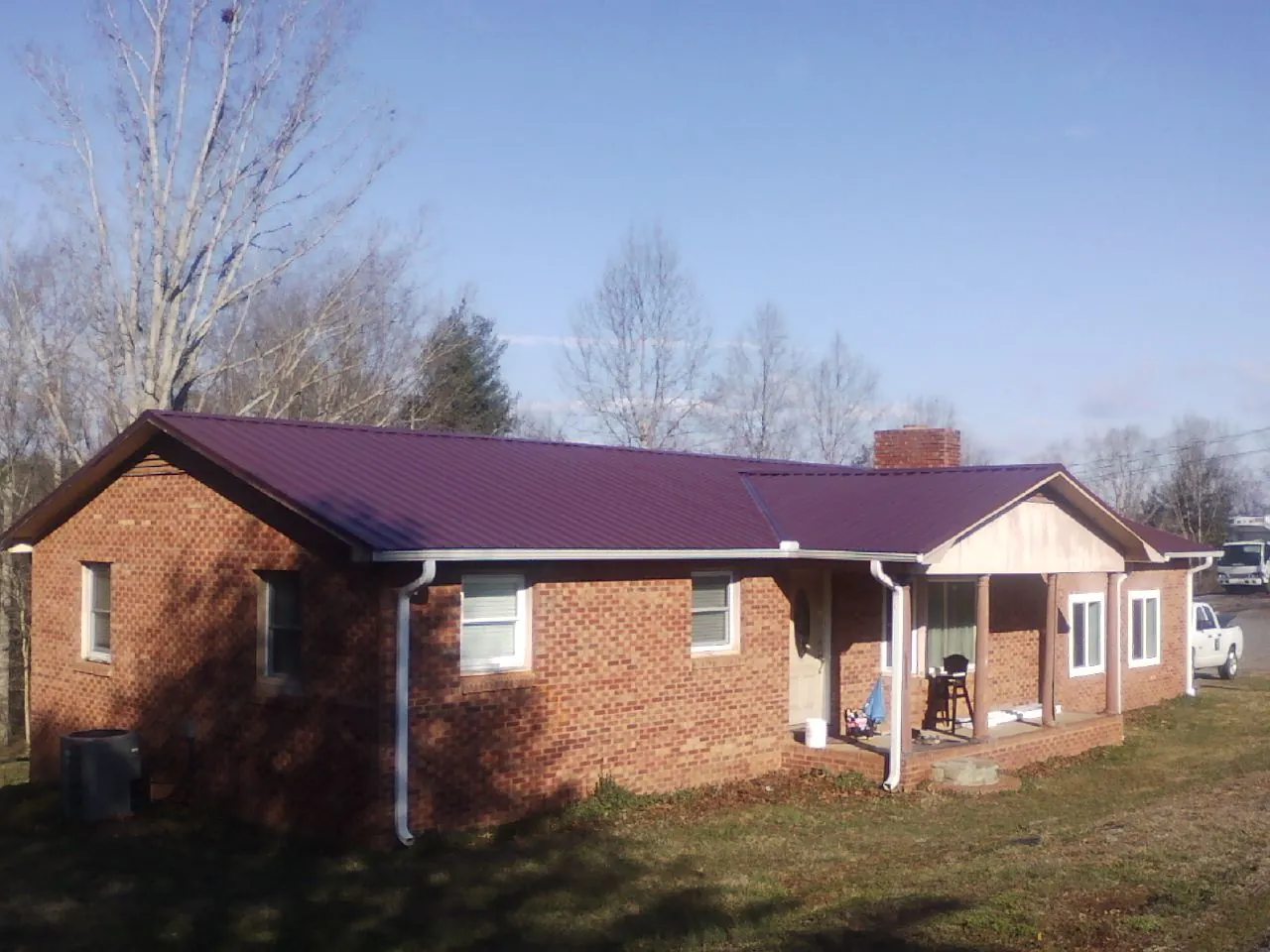 Burgundy metal roof on a brick ranch home with a new addition in Old Saybrook