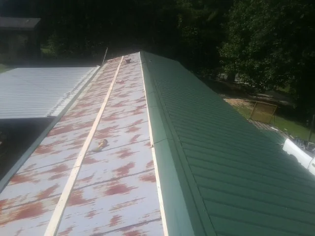 Old rusted panels beside newly installed green metal roofing — Wind Damage Roof Repair by Roofing Brothers in Old Saybrook