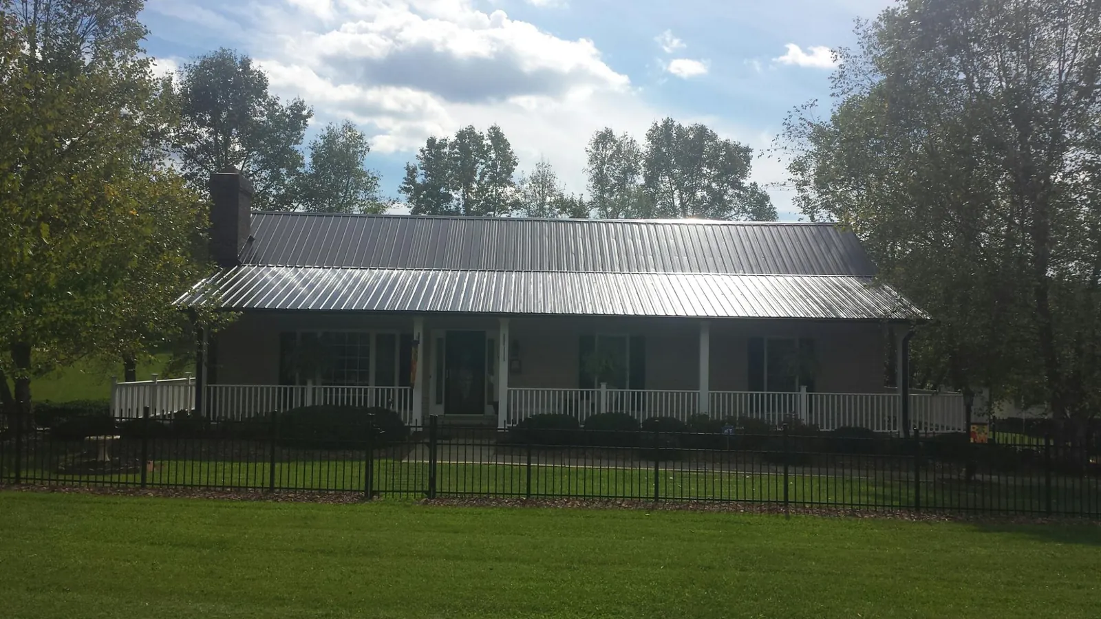 Gray metal roof on a brick ranch with a full width front porch — Gutter Guard Installation work by our crew in Old Saybrook