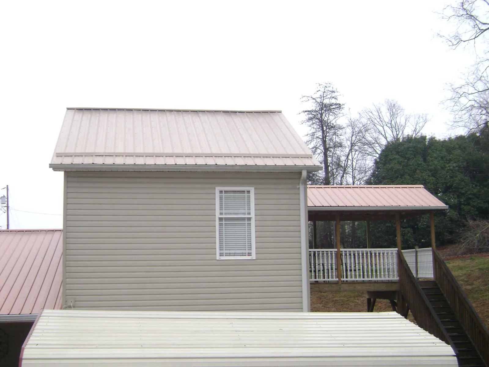 Tan metal roofs on a two story addition and attached porch, from a Roof Replacement job in Old Saybrook