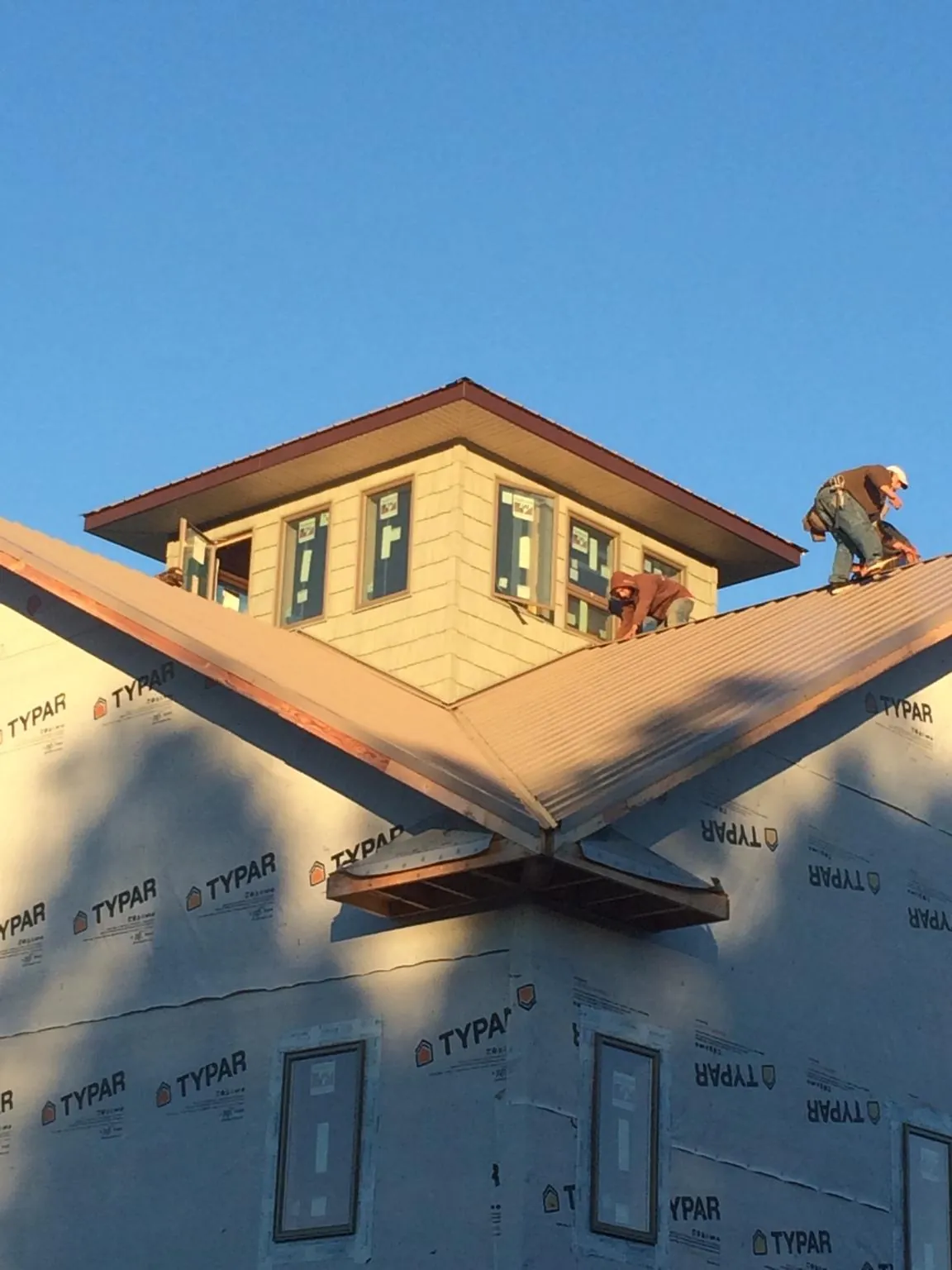 Roofers working around a rooftop cupola on a new metal roof at sunset — Roof Waterproofing in Old Saybrook by Roofing Brothers